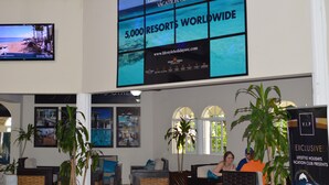 Un espace d’accueil doté d’un grand écran numérique affichant des publicités pour 5 000 stations de vacances dans le monde entier, d’un écran de télévision et de plusieurs plantes en pot.