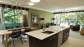 Una cocina moderna con una isla grande, comedor con sillas y vistas al exterior.