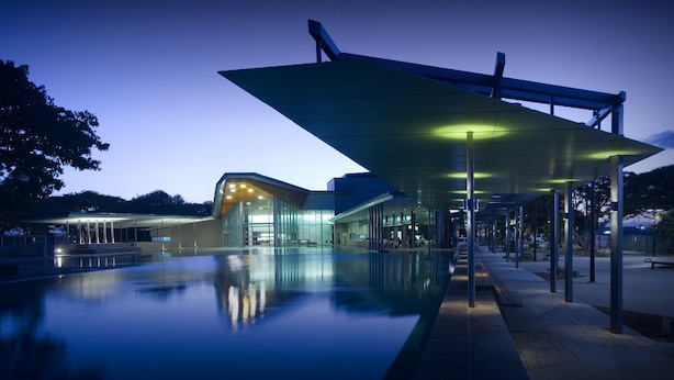 Un edificio moderno con fachada de vidrio y un área exterior cubierta con piscina.