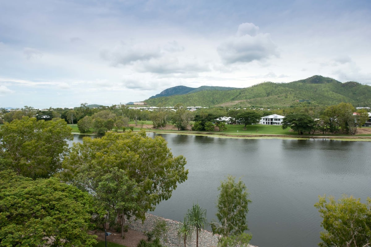 A lake with surrounding greenery and hills in the background.