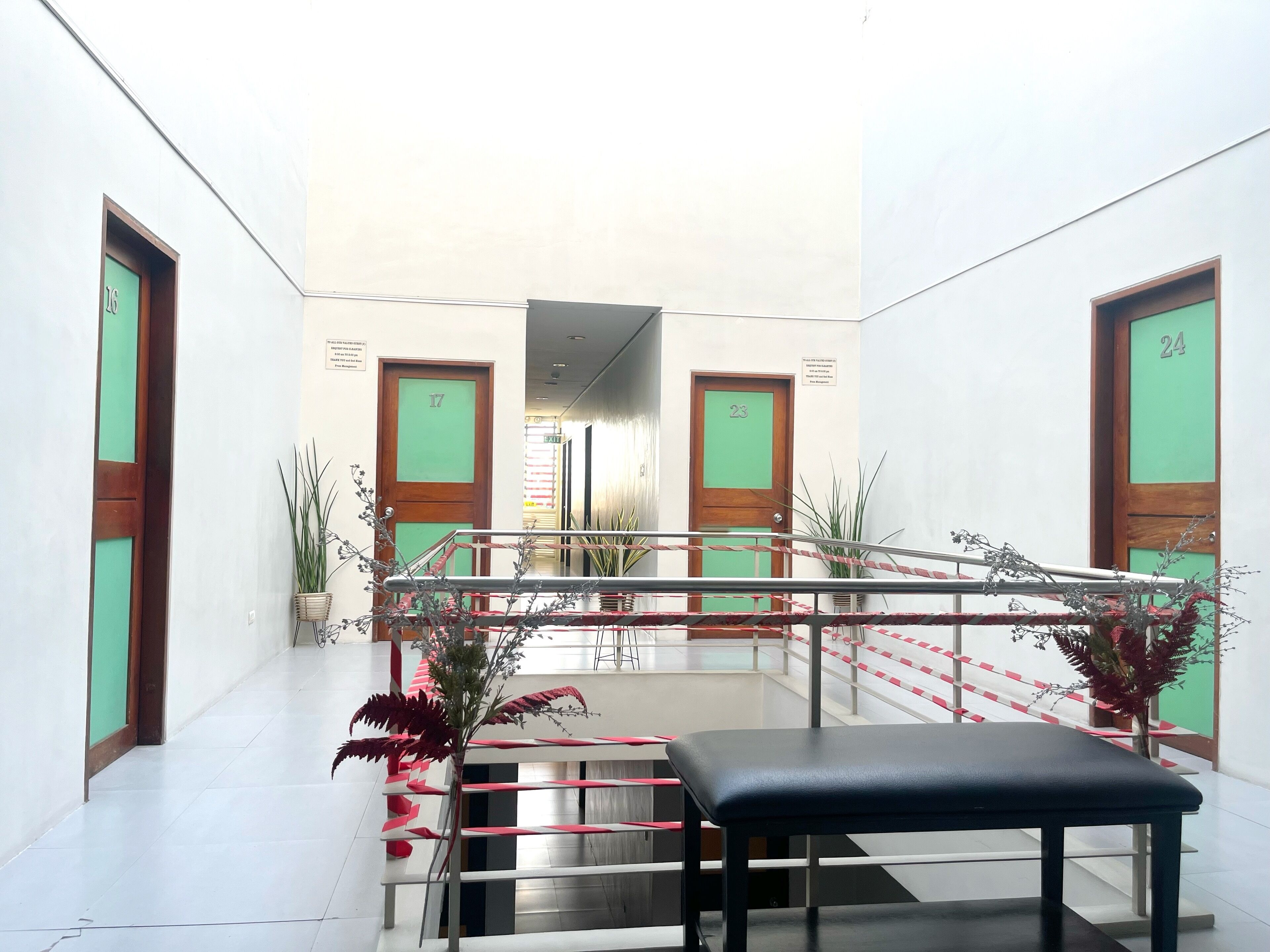 A hotel lobby with a central staircase, a reception desk, and a bench.