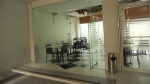 Un interior moderno con un separador de vidrio, suelo a cuadros y un comedor con sillas y una mesa.