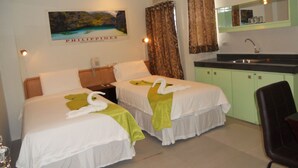 Habitación de hotel con dos camas, una kitchenette pequeña, un baño y un cuadro de Filipinas en la pared.