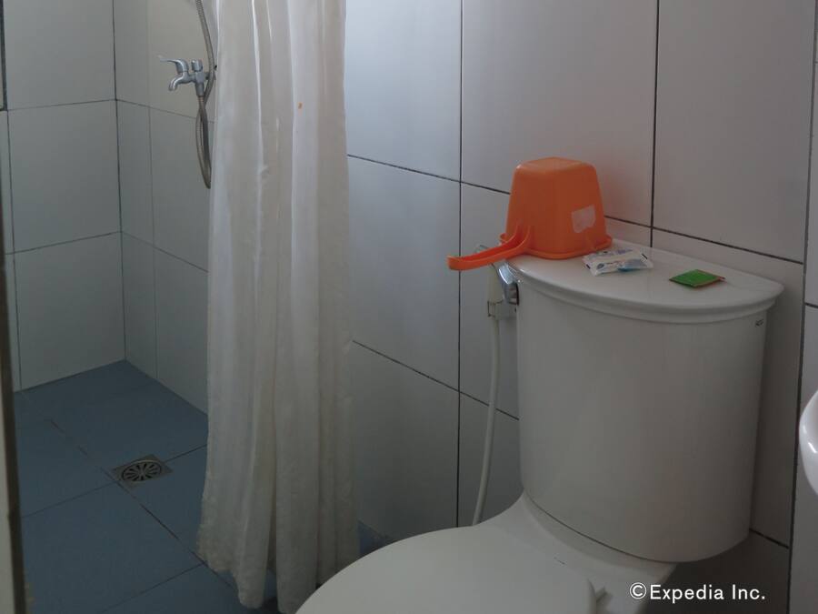 A small, tiled bathroom with a shower, toilet, and a window.