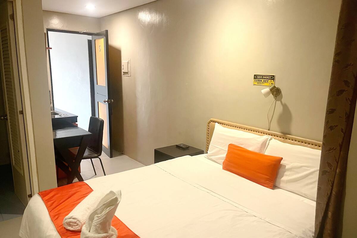 Quarto de hotel com cama, escrivaninha e cadeira.