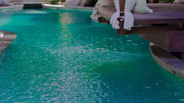 A thatched-roof structure with a hanging white curtain, adjacent to a clear blue pool surrounded by lush greenery. - The Dipan Resort Petitenget (Keroboken Kelod)