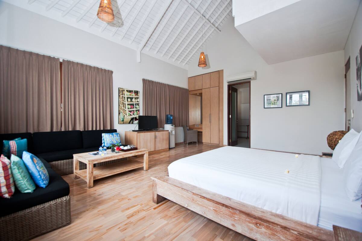 Una habitación moderna con una cama grande, un sofá, una mesa de centro de madera, un escritorio y un armario.