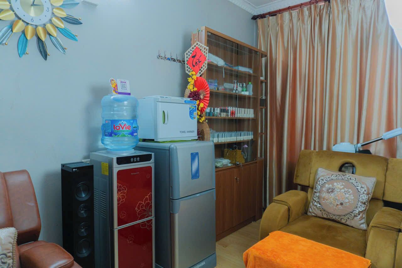 A living room with a sofa, a water dispenser, a refrigerator, a cabinet, and a fan.