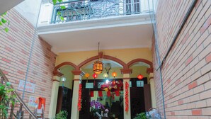 A narrow alleyway with a small shop entrance, brick walls, and a balcony with metal railings. - Il Divo Hostel (Hanoi)