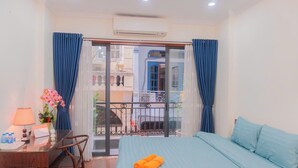 A hotel room with a bed, a desk, a chair, a balcony with a view, and an air conditioning unit. - Il Divo Hostel (Hanoi)