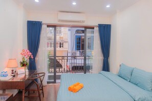 Habitación de hotel con cama, escritorio, silla, balcón con vistas y aire acondicionado.