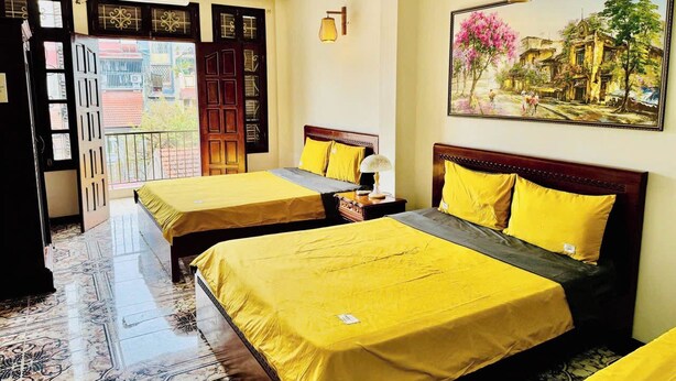 A hotel room with two beds, a balcony, a painting, and a ceiling fan. - Il Divo Hostel (Hanoi)