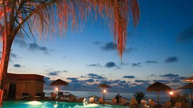 A swimming pool with a circular hot tub area, surrounded by lounge chairs and umbrellas, under a twilight sky. - Baia Tropea Resort (Parghelia)