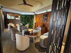 A modern lounge area with comfortable seating, a ceiling fan, and a green wall. - Gold Crest Hotel (Quatre Bornes)