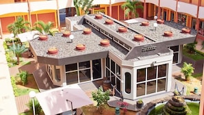 Un hotel con jardín en la azotea, mesas al aire libre y piscina.