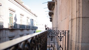 A view from a balcony with ornate metal railings, a stone building with classical architecture, and a clear sky. - Hotel Historia (Morelia)