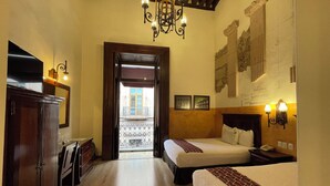 A hotel room with two beds, a wooden wardrobe, a desk, and a chandelier. - Hotel Historia (Morelia)