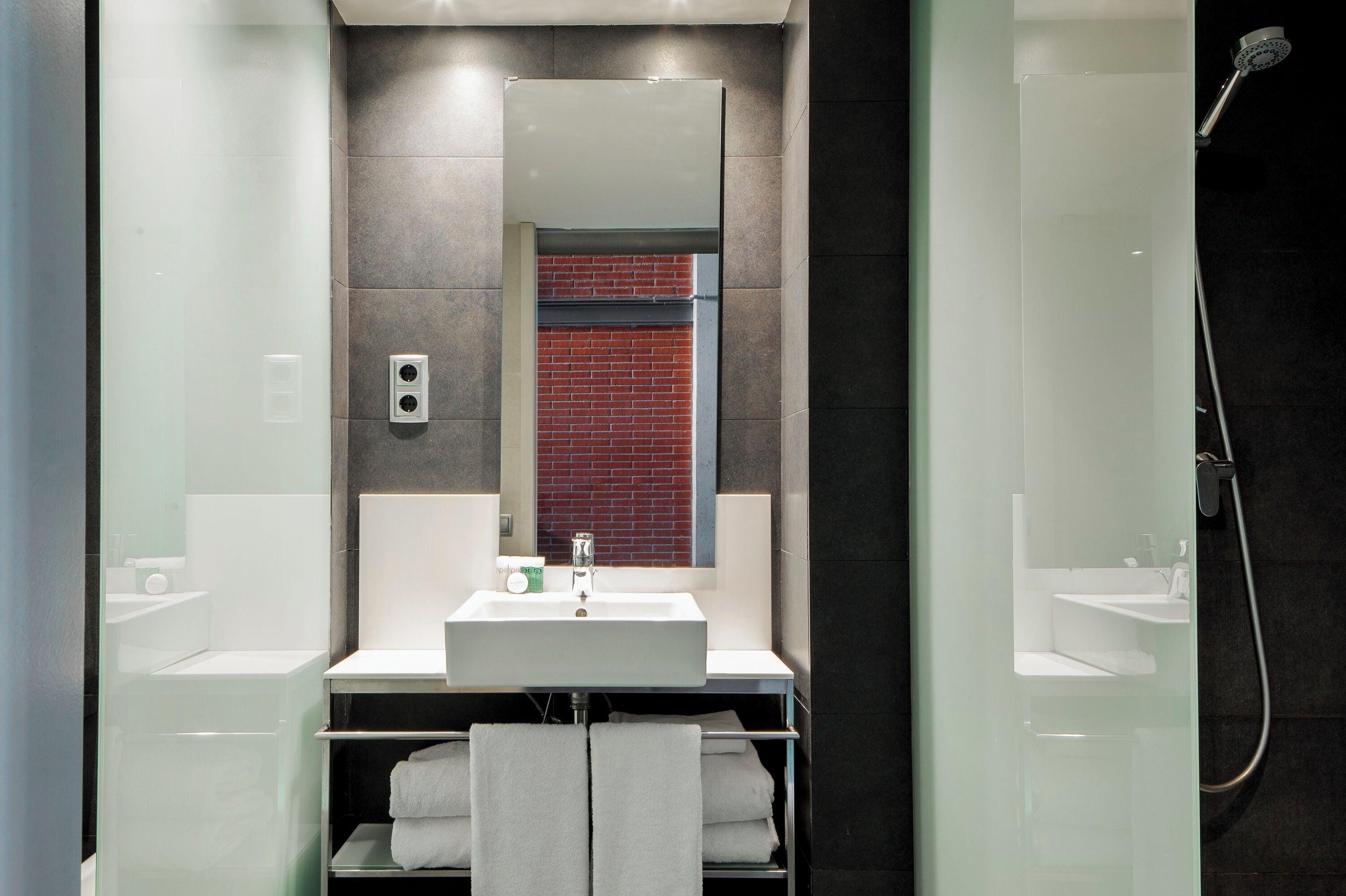 Een moderne badkamer met een douchecabine van glas, een wit wastafelmeubel en een spiegel erboven.