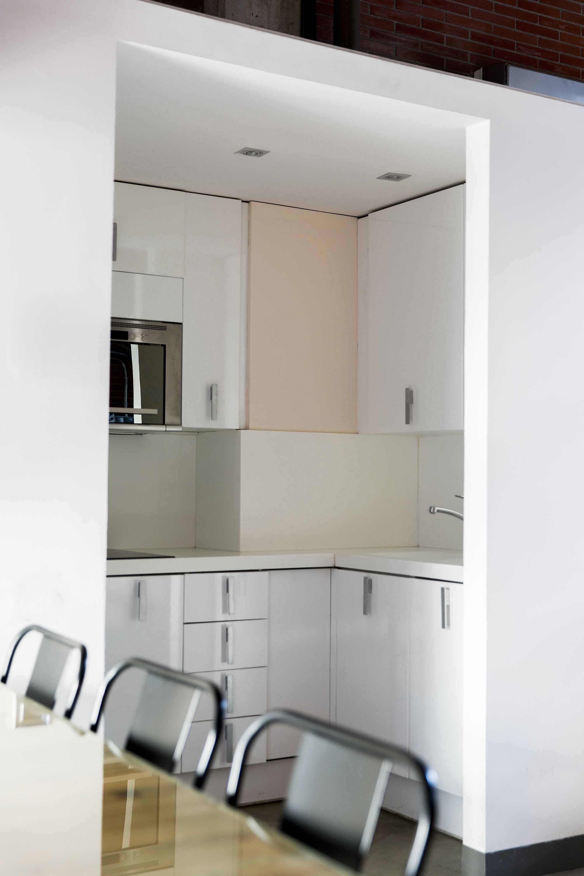 Een moderne keuken met witte kasten, een roestvrijstalen oven en een eethoek met een tafel en stoelen.