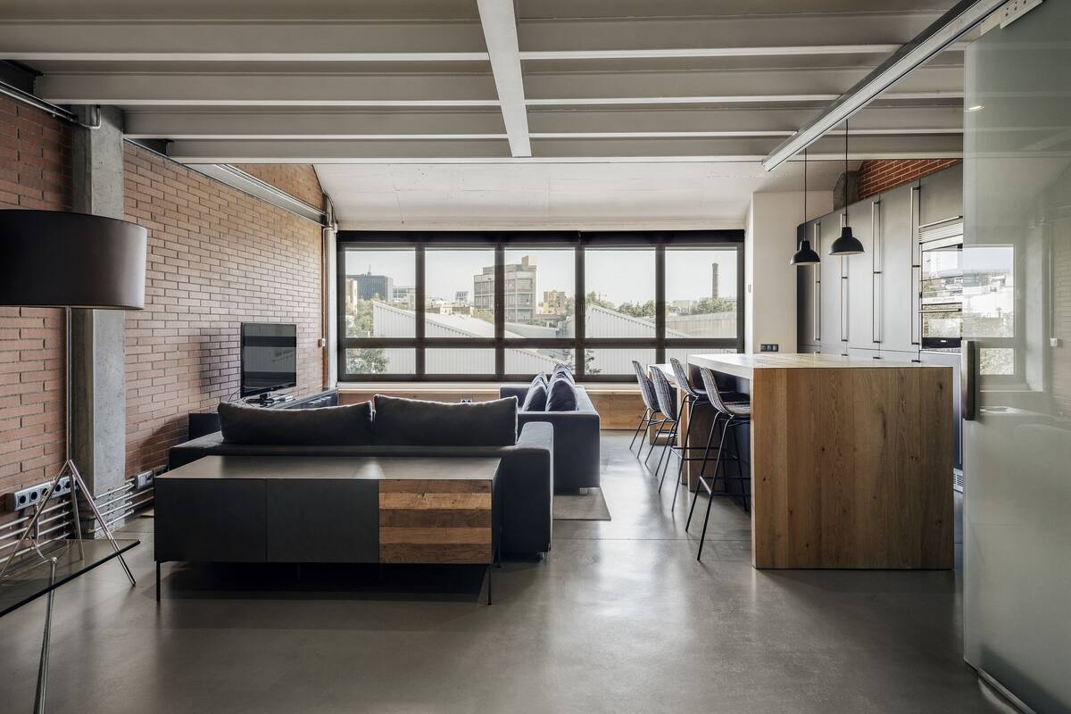A modern living space with a sofa, a wooden coffee table, and a kitchen area with a wooden counter.