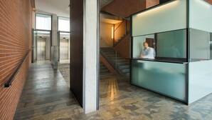 A modern interior with a brick wall, a glass partition, and a staircase. - Aparthotel República (Barcelona)
