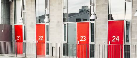 Un hotel de varios pisos con puertas rojas, numeradas del 11 al 24.