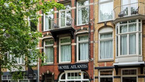 Un hotel de varios pisos con fachada de ladrillo, múltiples ventanas y un letrero que dice "HOTEL ATLANTIS".