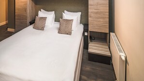 Un dormitorio moderno con tragaluz, cama con ropa blanca, cabecera de madera y un banco empotrado.