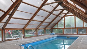An indoor swimming pool with a glass ceiling, a diving board, and a small white stool. - Portal de Piedra (Villa La Angostura)