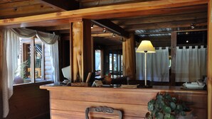 A wooden reception desk with a lamp, a chair, and a potted plant. - Portal de Piedra (Villa La Angostura)