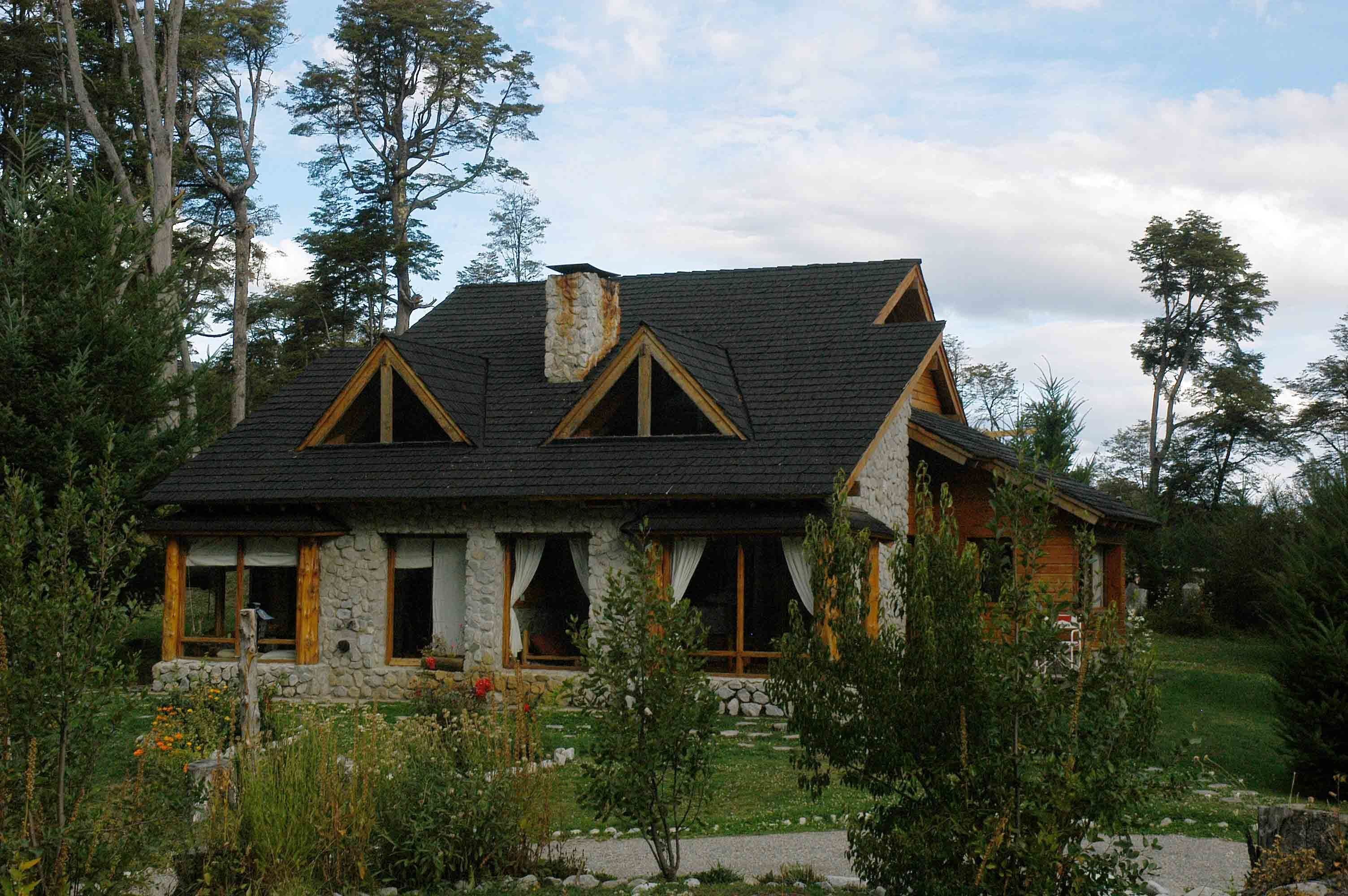 Una casa de piedra con techo oscuro, marcos de madera y chimenea de piedra.