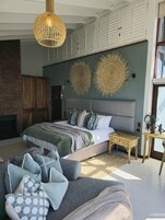A modern bedroom with a large bed, a fireplace, and a dining area.