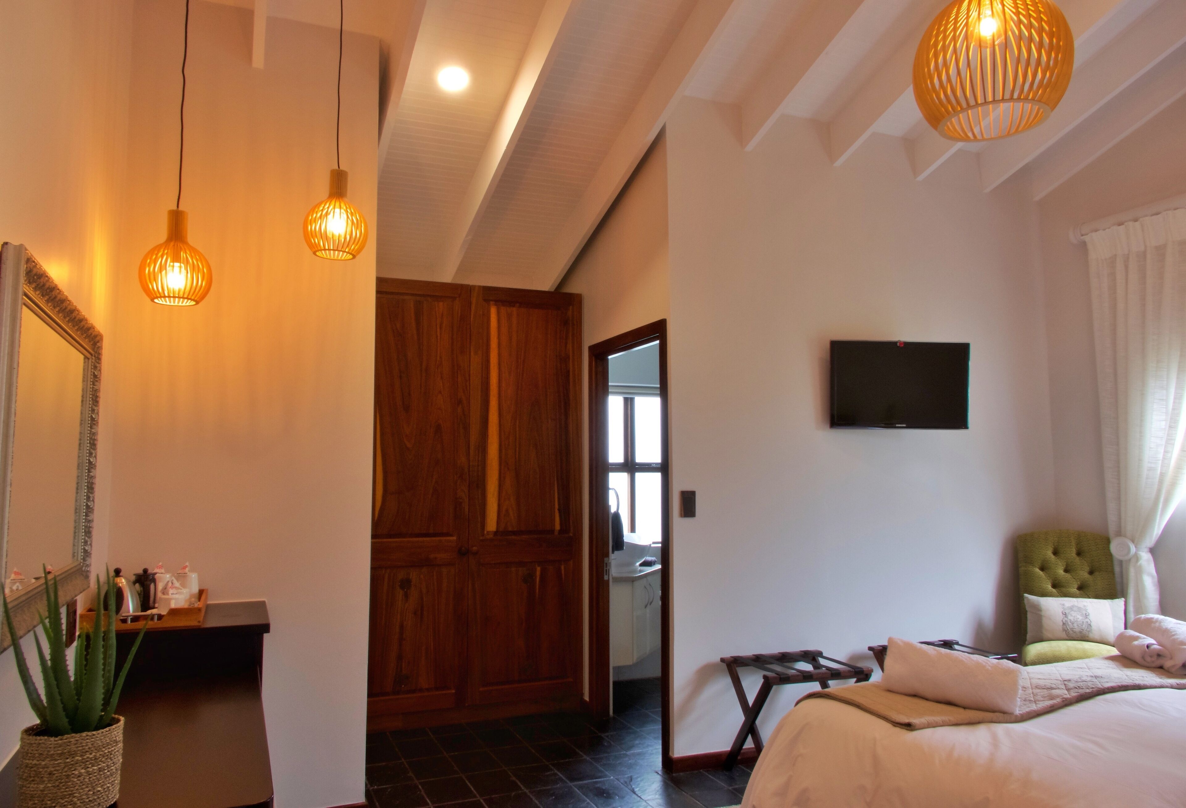 Um quarto com uma cama, televisão e porta de madeira.