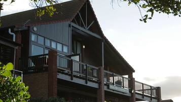 A two-story building with a balcony and a sign that reads "Shaloh Guesthouse."
