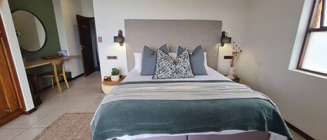 A bedroom with a bed, bedside tables, a mirror, and a door.