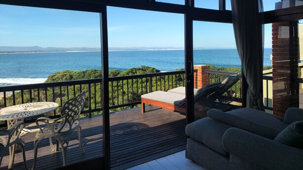 A balcony with a view of the ocean, a table, chairs, and a sofa. - Shaloha Guesthouse on Supertubes (Jeffreys Bay)