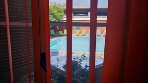Vista a través de una ventana con piscina y mobiliario exterior.