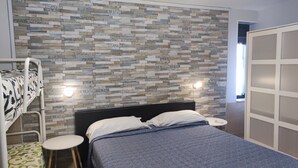 Un dormitorio con una cama, una litera, una mesita de noche y una pared con diseño de mosaico.