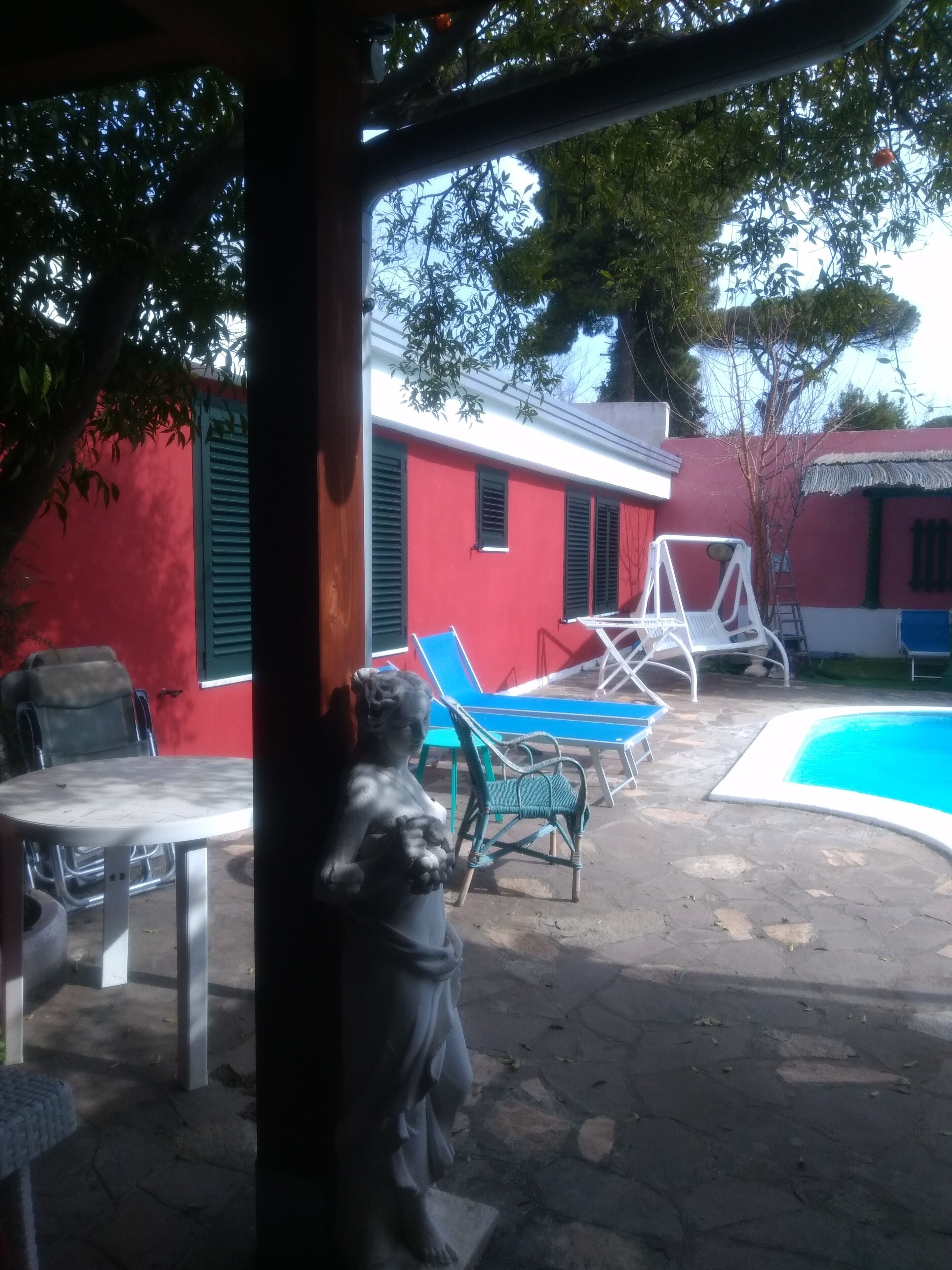 A courtyard with a swimming pool, outdoor furniture, and a statue.