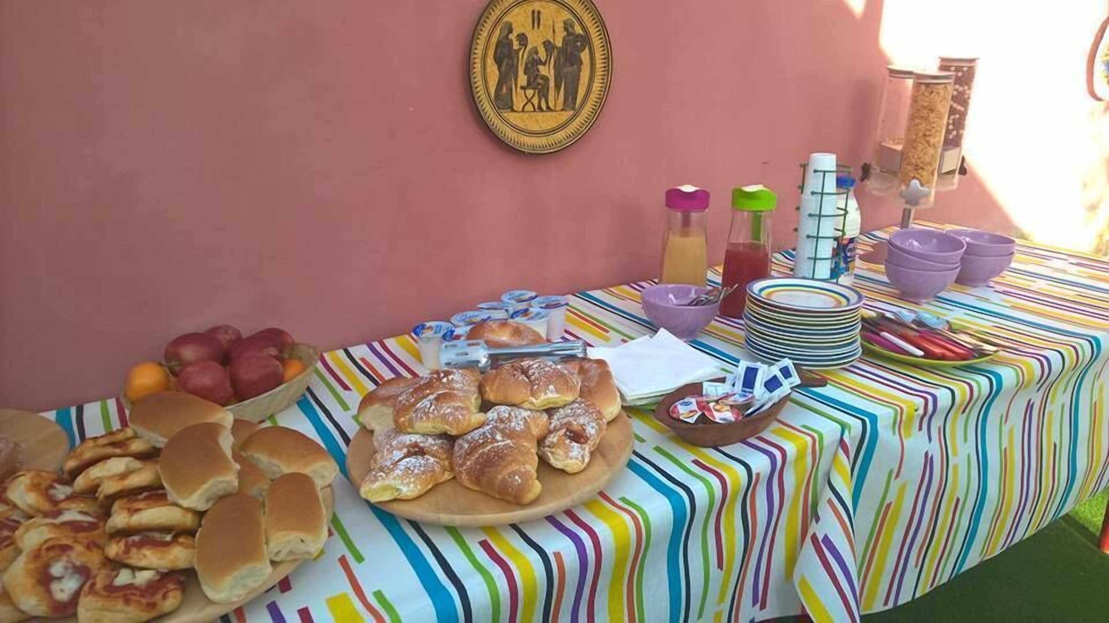 En frukostbuffé med bakverk, frukt och drycker, uppdukad på ett randigt bordsduks.