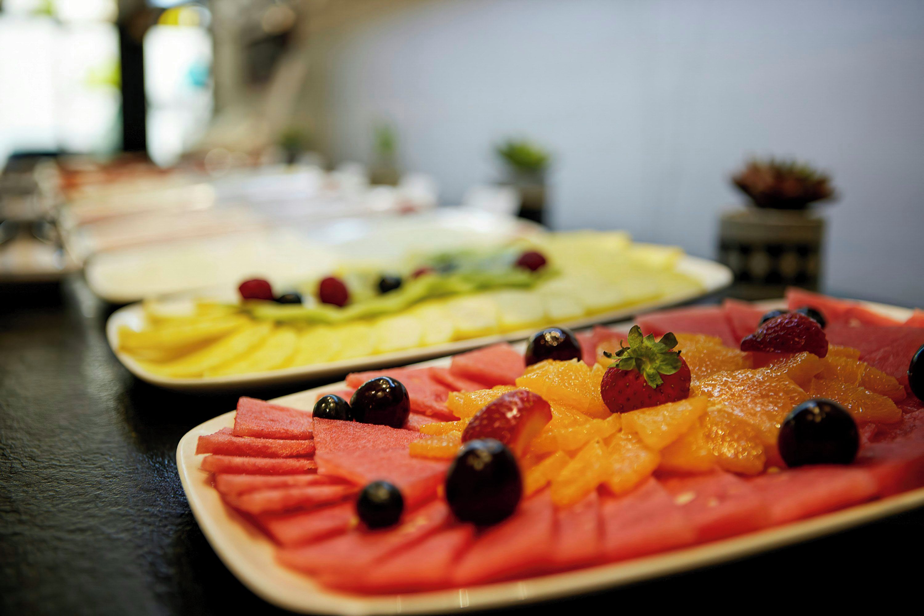 Una bandeja de frutas con sandía, fresas y naranjas.