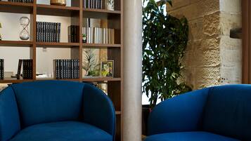 Una habitación con dos sofás azules, una estantería de madera y una planta grande.