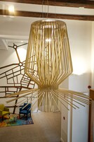 Um interior moderno com uma luminária pendente única, uma escada com design geométrico na parede e um tapete colorido.