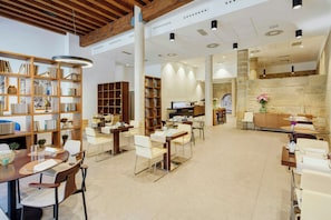 A spacious library with multiple seating areas, bookshelves, and a stone wall. - Sercotel Calle Mayor (Logroño)