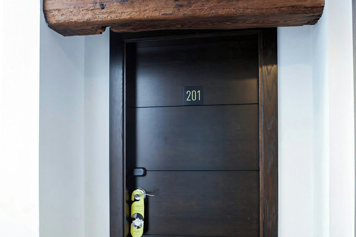 A dark wooden door with a number plate, a doorbell, and a keyhole.