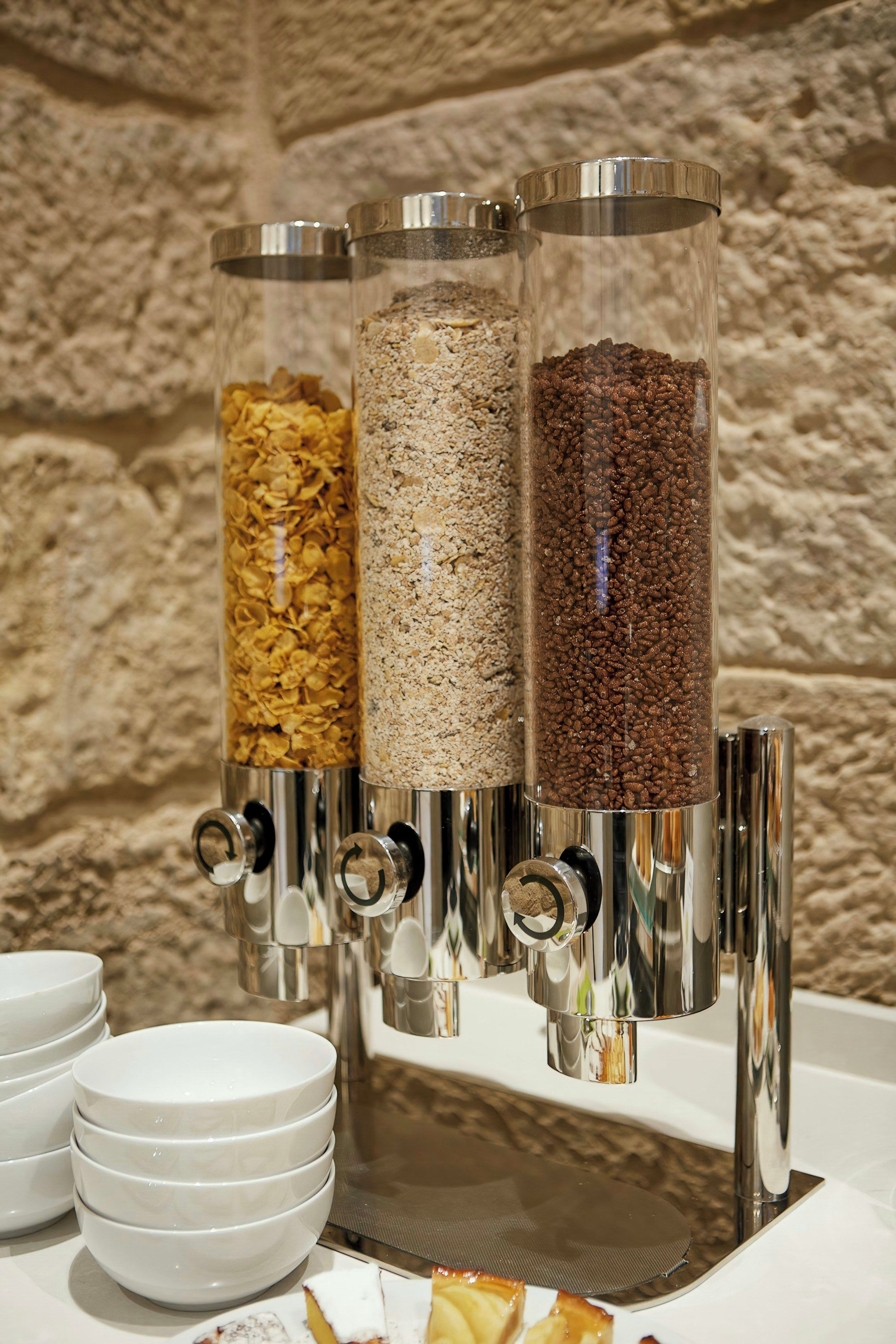 Una estación de dispensación de alimentos con tres recipientes de cereales y escamas variados.