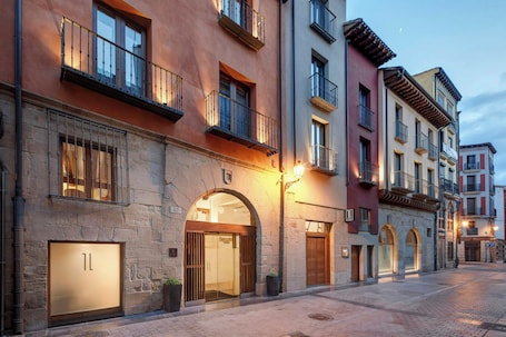 A street with a hotel entrance, stone facade, and multiple balconies.
