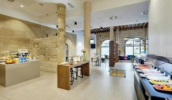 Um hall de hotel com área de buffet, paredes de pedra e espaço de estar com mesas e cadeiras.