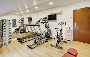 Un gimnasio con cintas de correr, elípticas y una jaula de pesas.