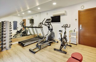 Un gimnasio con cintas de correr, elípticas y una jaula de pesas.